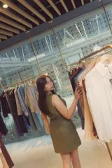 Vestido corto verde de cuero sintético, sin mangas, con cierre frontal de cremallera y cinturón con hebilla.