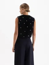 Top sin mangas de cuello redondo y corte cropped, confeccionado en tejido de angora y lana con textura suave. Presenta apliques metálicos en forma de corazón distribuidos por toda la prenda.