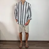 Camisa de manga larga con cuello mao, confeccionada en tejido de lino a rayas verticales en tonos blanco y celeste. Presenta cierre frontal con botones y corte clásico.