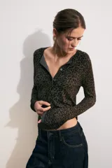 Chaqueta de punto de manga larga y cuello redondo, con cierre frontal de botones y estampado animal print en tonos marrones y negros.