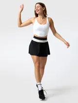 Top deportivo blanco con costuras visibles tipo corseteras en el pecho, tirantes delgados y espalda rebajada.