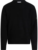 Sweater negro de lana y acrílico con cuello redondo, puños y bajo de canalé. Tiene una insignia con el logo de Calvin Klein en la manga.