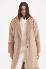 Tapado largo de gamuza color chocolate con detalles de corderito en solapas, puños y ruedo. Presenta cierre frontal con botones y corte recto.