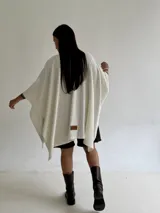 Ruana de tejido de punto trenzado en color crudo, con diseño abierto, corte holgado y mangas amplias tipo kimono.