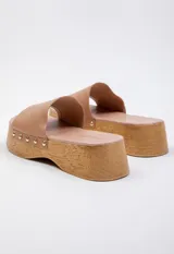 Sandalia de plataforma alta color negro, con capellada de cuero y remaches metálicos. Cuenta con plantilla de cuero sintético y plataforma símil madera de 5 cm de alto.