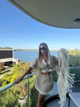 Falda corta color beige, confeccionada en lino, con detalle de puntilla blanca en el ruedo y diseño de corte recto.