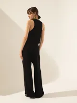 Pantalón negro de crepe con cintura cruzada, broche con brillo glitter, tiro alto, pinzado y pata ancha.