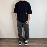 Pantalón jean cargo negro con corte holgado y múltiples bolsillos.