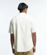 Camisa de corte relajado para hombre, confeccionada en una mezcla de cáñamo y algodón. Presenta cuello inglés, manga corta, cierre frontal con botones y un bolsillo en el pecho con una pequeña etiqueta aplicada.