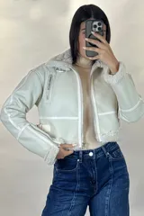 Campera tipo gamulán de cuero sintético negro, con interior y detalles de cuello y puños en corderito blanco. Presenta cierre frontal, cierres en los puños y correas ajustables en la cintura.