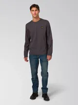 Remera de manga larga color gris oscuro, con cuello redondo y puños acanalados. Presenta un pequeño parche rectangular con el logo de la marca en el lado izquierdo del pecho.