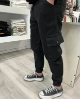 Pantalón cargo slouchy de color negro, corte holgado con bolsillos laterales con solapa y puños elásticos en los tobillos.
