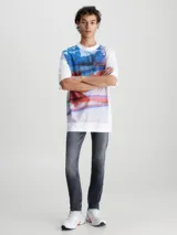 Pantalón de jean gris oscuro de corte slim, con cintura media, cinco bolsillos y cierre con cremallera.