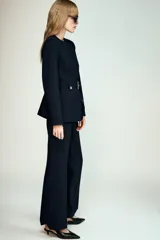 Blazer de cuello redondo y manga larga, color azul marino. Presenta un diseño entallado con cinturón integrado del mismo tejido, hebilla metálica dorada y cierre frontal con botones a presión ocultos.