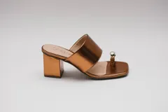 Sandalias de cuero color bronce con taco cuadrado y tira ancha sobre el empeine. Presentan un aro metálico plateado que separa el dedo gordo del resto.