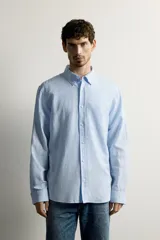 Camisa regular fit celeste confeccionada en mezcla de lino y algodón, con cuello abotonado, manga larga, bolsillo frontal en el pecho y cierre de botonadura.