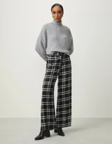 Pantalón de vestir negro con estampado de cuadros blancos, corte palazzo y cintura alta con cinturón.