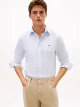 Camisa de manga larga de Tommy Hilfiger confeccionada en popelín de algodón con tecnología flex, con diseño de rayas clásicas en celeste y blanco, corte clásico, cuello con botones y el logo bordado en el pecho.