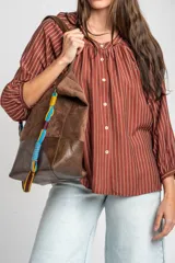 Blusa de manga larga con diseño a rayas verticales, cuello redondo con pequeña abertura frontal abotonada y mangas con puños elásticos.