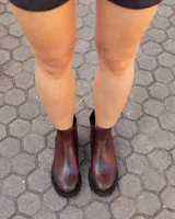 Botas tipo Chelsea de cuero color chocolate, con paneles elásticos laterales, suela track dentada y detalle de textura en el talón.