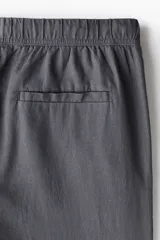 Pantalón gris de corte recto y relajado, con cintura elástica ajustable con cordón, bolsillos laterales y trasero. Confeccionado en mezcla de lino y viscosa.