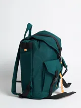 Mochila acolchada de nylon color negro con correas y detalles en rosa pálido. Presenta un cierre principal tipo solapa con hebilla de plástico negra y una cinta colgante con el texto "rusty" en color verde menta.