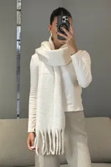 Bufanda de tejido grueso y suave, color blanco, con diseño de flecos en los extremos.