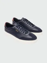 Zapatillas Boss modelo Kieran Tenn, confeccionadas en una combinación de cuero texturizado y gamuza en color azul marino. Presentan suela de goma blanca, cordones al tono y detalle de logo en color dorado en el lateral y talón en contraste.