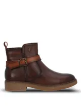 Botines de cuero color marrón oscuro, con diseño de caña media, cierre lateral y una tira decorativa con hebilla metálica sobre el empeine. Presentan una suela de goma texturizada en tono natural y un pequeño logo metálico en la parte superior de la caña.