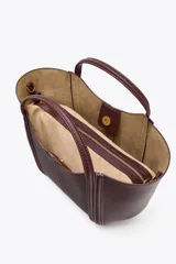 Bolso de mano tipo mini city, color borgoña, con pespuntes en contraste. Presenta asa de mano y asa bandolera extraíble. Incluye una bolsa interior extraíble con cierre de cremallera.