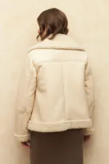 Campera gamulán negra con cuello, puños y ruedo de corderito. Tiene cierre frontal con cremallera y bolsillos laterales.