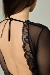 Conjunto de lencería negro de encaje y tul, compuesto por un bralette de manga larga con escote en V y una bombacha tipo tanga con detalles de encaje.