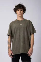 Remera de corte holgado con efecto de lavado ácido en tono gris oscuro. Presenta un pequeño estampado gráfico en el centro del pecho con la inscripción 'ASTRAL ENERGY' y las siglas 'VCP'.