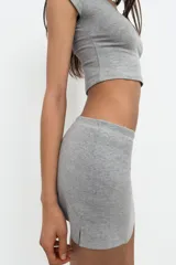 Falda corta gris melange de tiro medio con cintura elástica, confeccionada en hilatura con mezcla de algodón. Cuenta con forro interior tipo shorts del mismo tejido.