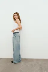 Jeans de tiro medio con cinco bolsillos, cintura doble a contraste y detalles de rotos. Cierre frontal con cremallera y botones metálicos.