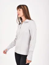 Buzo deportivo gris claro con cuello alto y cierre frontal parcial. Tiene mangas largas con orificios para los pulgares y costuras decorativas que realzan la figura.