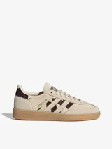Championes Adidas Handball Spezial de diseño clásico, confeccionados en gamuza color crema con detalles de estampado animal print en las icónicas tres tiras y el talón. Presentan suela de goma color caramelo y logo dorado en el lateral.
