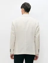 Blazer de medio forro color beige, confeccionado en mezcla de algodón y lino. Presenta una silueta estructurada con solapas de muesca, cierre frontal de un botón y bolsillos con solapa.