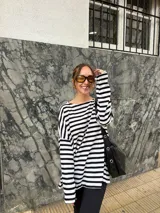 Conjunto compuesto por remera de manga larga oversize a rayas horizontales blancas y negras con escote bote, y pantalón negro de corte flared.