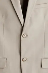 Blazer slim fit de botonadura sencilla en color beige, con solapas de muesca, bolsillos con solapa y cierre de botones.
