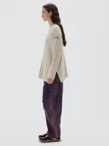 Buzo tejido de punto color beige, con cuello subido, diseño oversized y aberturas laterales en el ruedo.