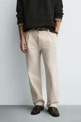 Pantalón relaxed fit color beige confeccionado en tejido de algodón con tacto suave, cintura con pliegues delanteros y cierre frontal con cremallera y botón.