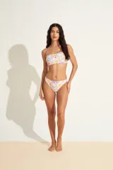 Top de bikini bandeau con estampado de flores y frutas en tonos blanco, naranja, violeta y verde. Tiene un tirante fino al cuello.