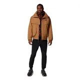 Campera técnica Columbia de estilo retro, color camel con forro interior en color rojo. Presenta cierre frontal con solapa, bolsillos frontales amplios, puños ajustables con velcro y cuello alto. Es una prenda versátil con sistema de intercambio que permite usar el forro por separado.