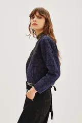 Campera corta acolchada color azul marino con cierre frontal y bordados florales en negro con cuentas y lentejuelas en el pecho y parte superior.