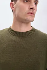 Sweater de punto color verde oliva, con cuello redondo y mangas largas. Diseño clásico con terminaciones acanaladas en cuello, puños y ruedo.