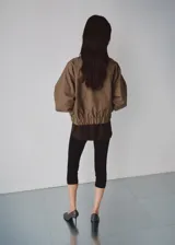 Chaqueta de diseño recto con estampado de pata de gallo, cuello alto y manga larga con puños elásticos. Cuenta con cierre delantero de cremallera y dos bolsillos con solapa en la parte delantera.