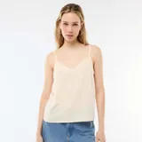 Camiseta de tirantes color beige, con escote en V decorado con detalle de encaje y tirantes finos ajustables.