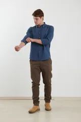 Camisa de vestir blanca de manga larga, con cuello abotonado, bolsillo frontal y botones en tono madera.