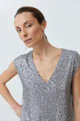 Vestido corto plateado con lentejuelas, escote en V y mangas cortas.